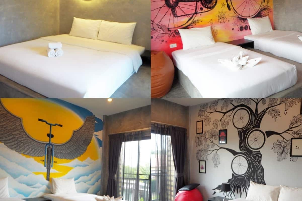A hotel room with a bed, a wall mural, and a window with curtains.