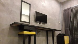 A room with a desk, a chair, a television, and a suitcase. - The Bike Loft Family Hostel (Hua Hin)