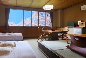 Una habitación japonesa tradicional con suelo de tatami, una mesa de madera baja y un televisor en un estante.