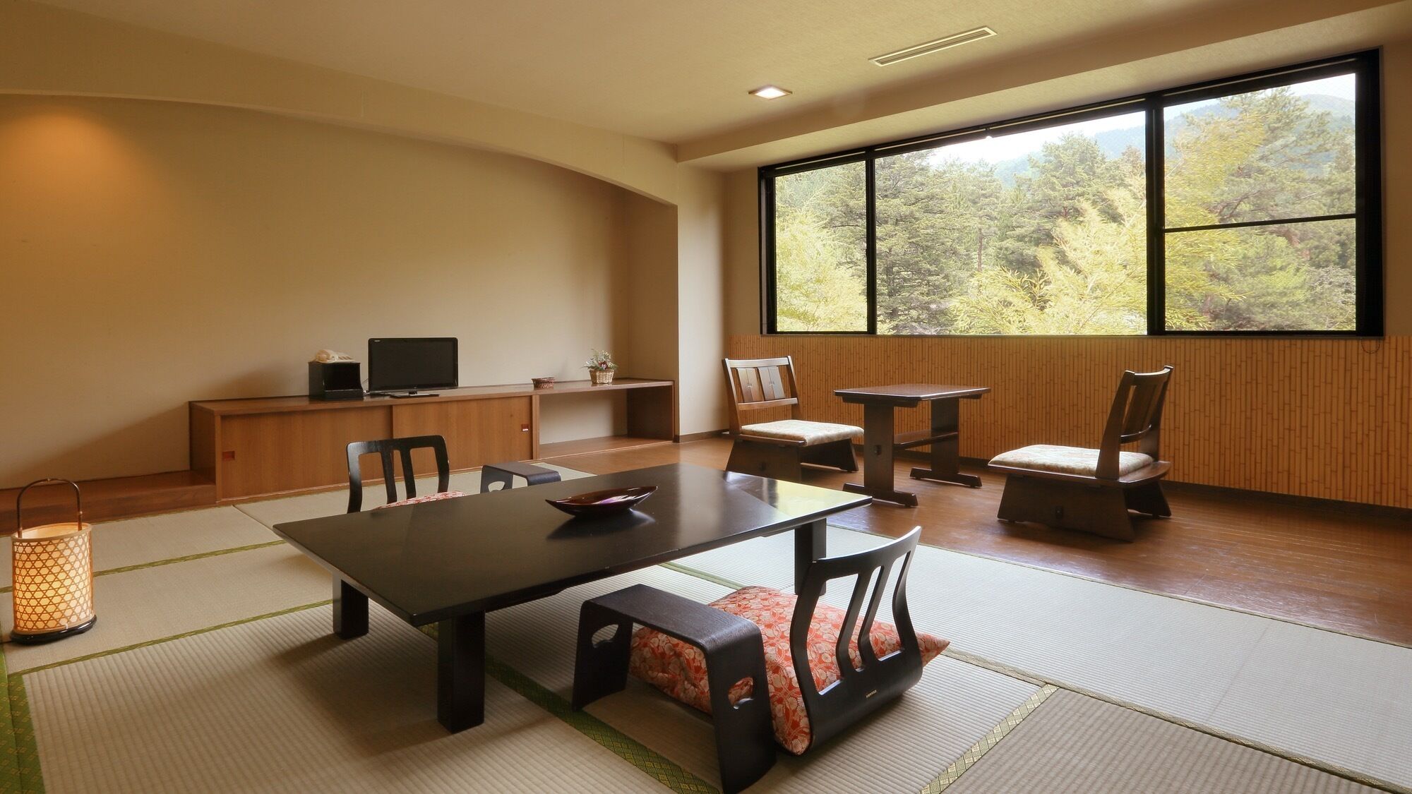 A traditional Japanese-style room with tatami flooring, a low table, and chairs.