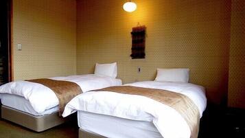 Une chambre avec deux lits, chacun équipé d’un matelas et d’oreillers, d’un luminaire suspendu et d’un mur à texture.