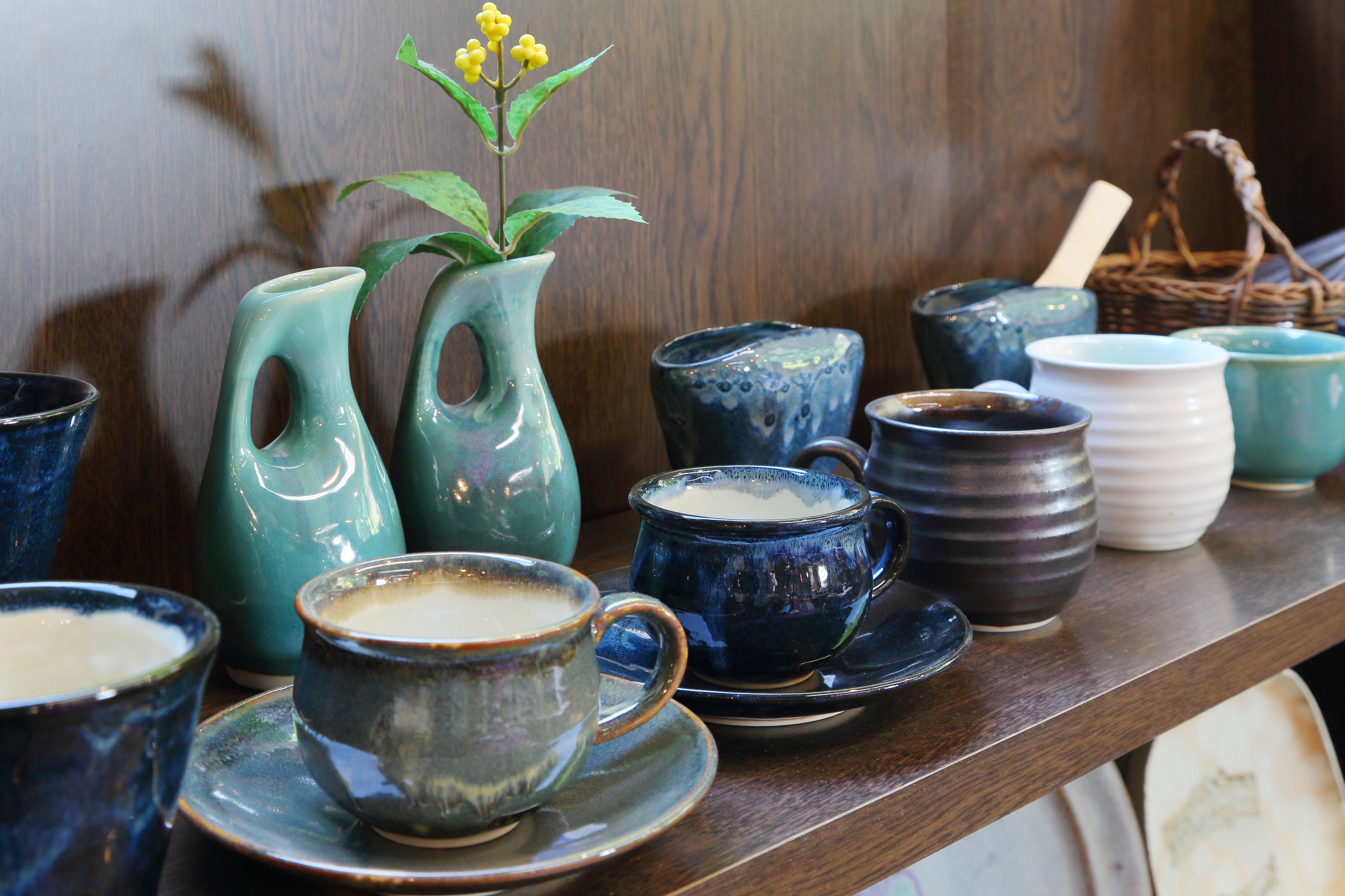 A variety of ceramic cups and vases on a shelf.