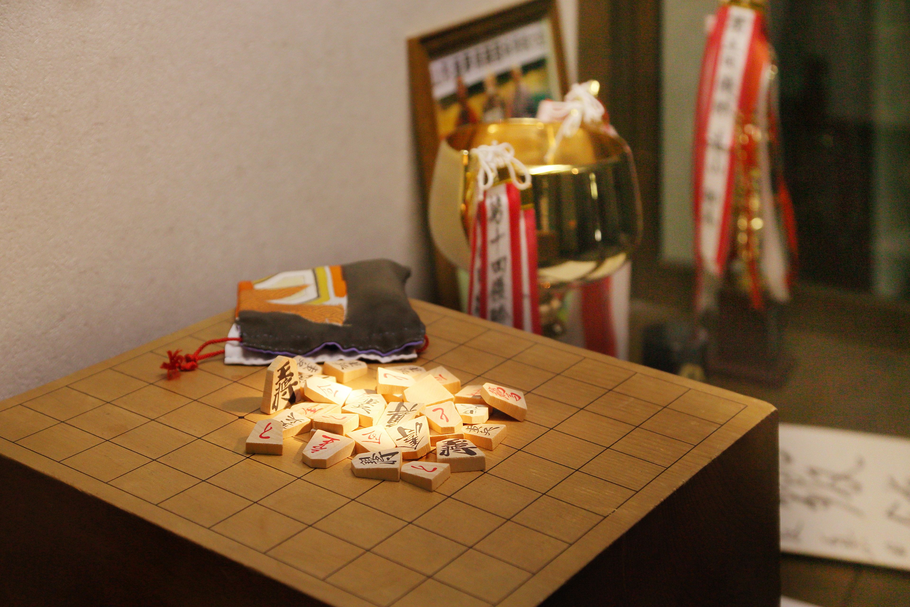 A Go board with pieces scattered on it, a pair of shoes, and a framed picture in the background.
