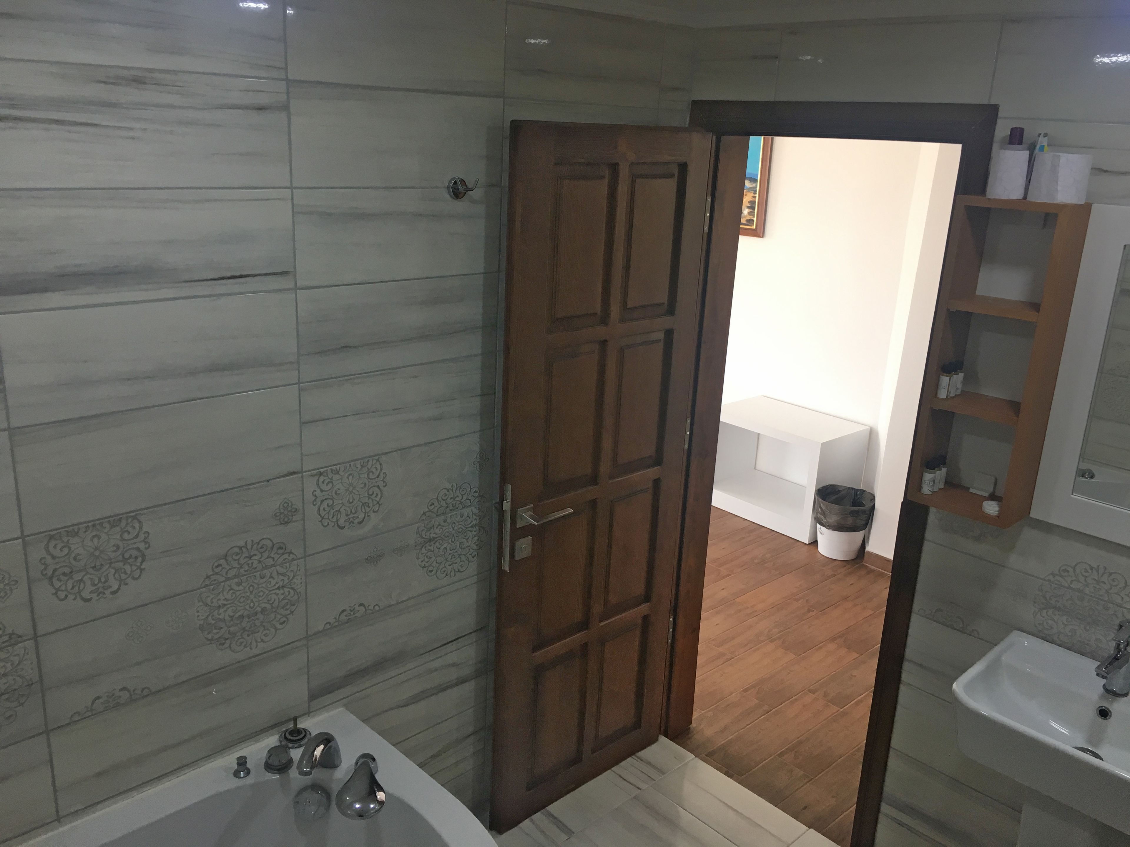 A bathroom with a wooden door, a bathtub, and a sink.