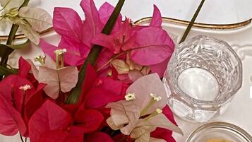 Una mesa servida con una taza de café, un vaso de agua, una galleta y un ramo de flores, junto con un menú del Hotel Elegance.