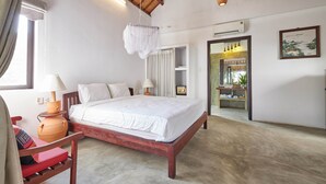 A bedroom with a wooden bed, white bedding, a red chair, a bedside table with a lamp, and a large window with curtains. - Blue Beach Village Homestay (Da Nang)