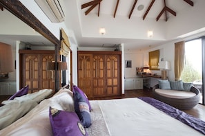 A spacious bedroom with a large bed, a seating area, and a view of the outdoors.