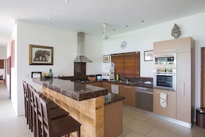 A modern kitchen with a central island, built-in oven, and stainless steel appliances.