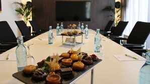A conference room with a long table set for a meeting, featuring a variety of pastries and beverages. - Hotel Tobbaccon (Bensheim)