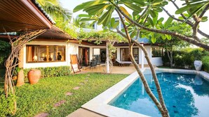 Zona junto a la piscina con vista despejada, un espacio de descanso techado y abundante vegetación.