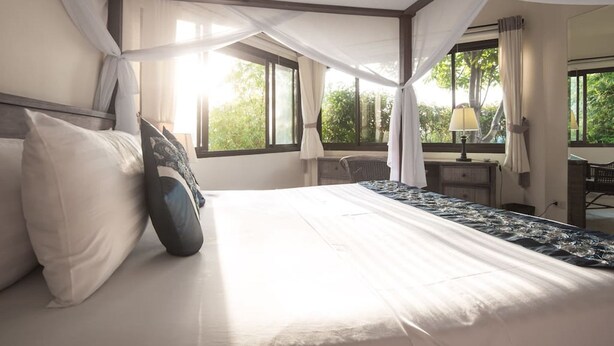 Una habitación de hotel con una cama grande, un escritorio y una ventana con cortinas.