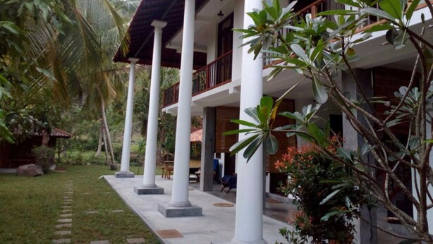 A two-story building with a covered patio area supported by white columns. - Vista Silva Rest (Unawatuna)