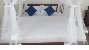 A bed with a canopy, two pillows, and a wooden headboard. - Vista Silva Rest (Unawatuna)
