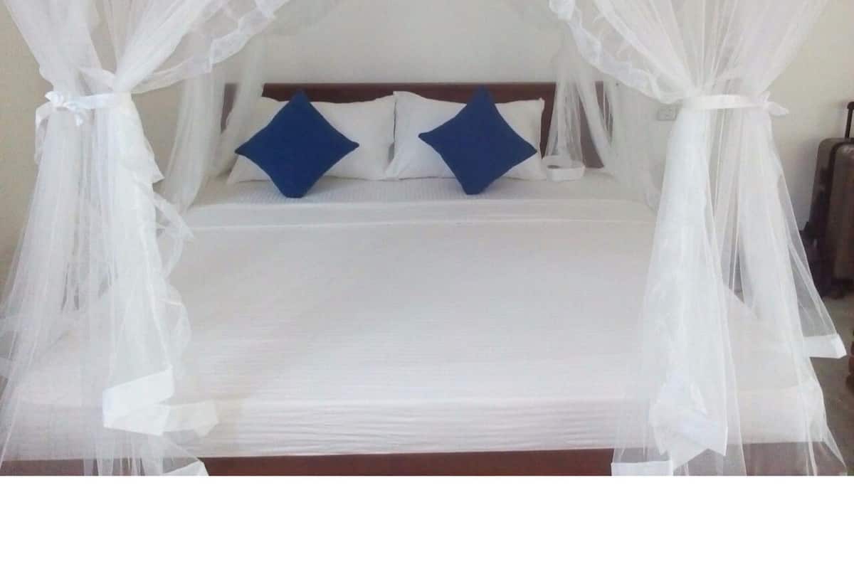 A bed with a canopy, two pillows, and a wooden headboard.