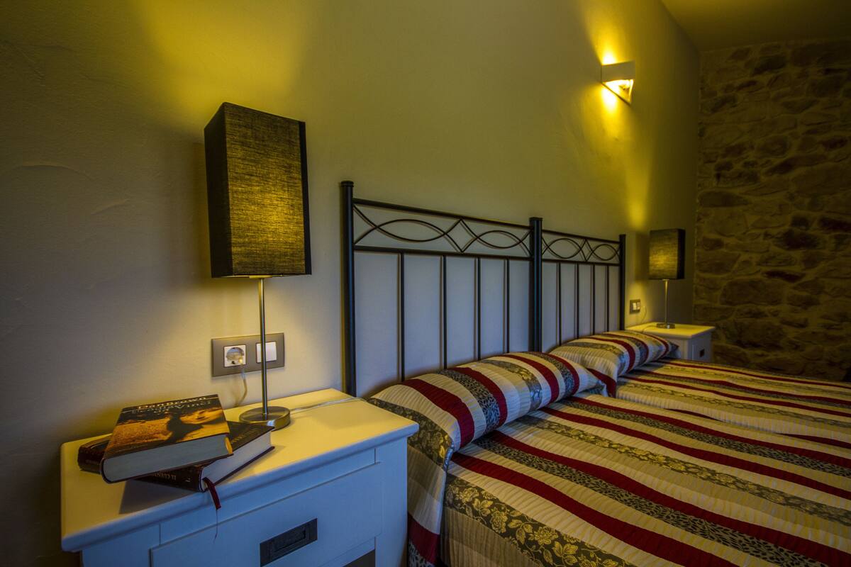 Un dormitorio con cama, mesitas de noche, una lámpara y una lámpara de pared.