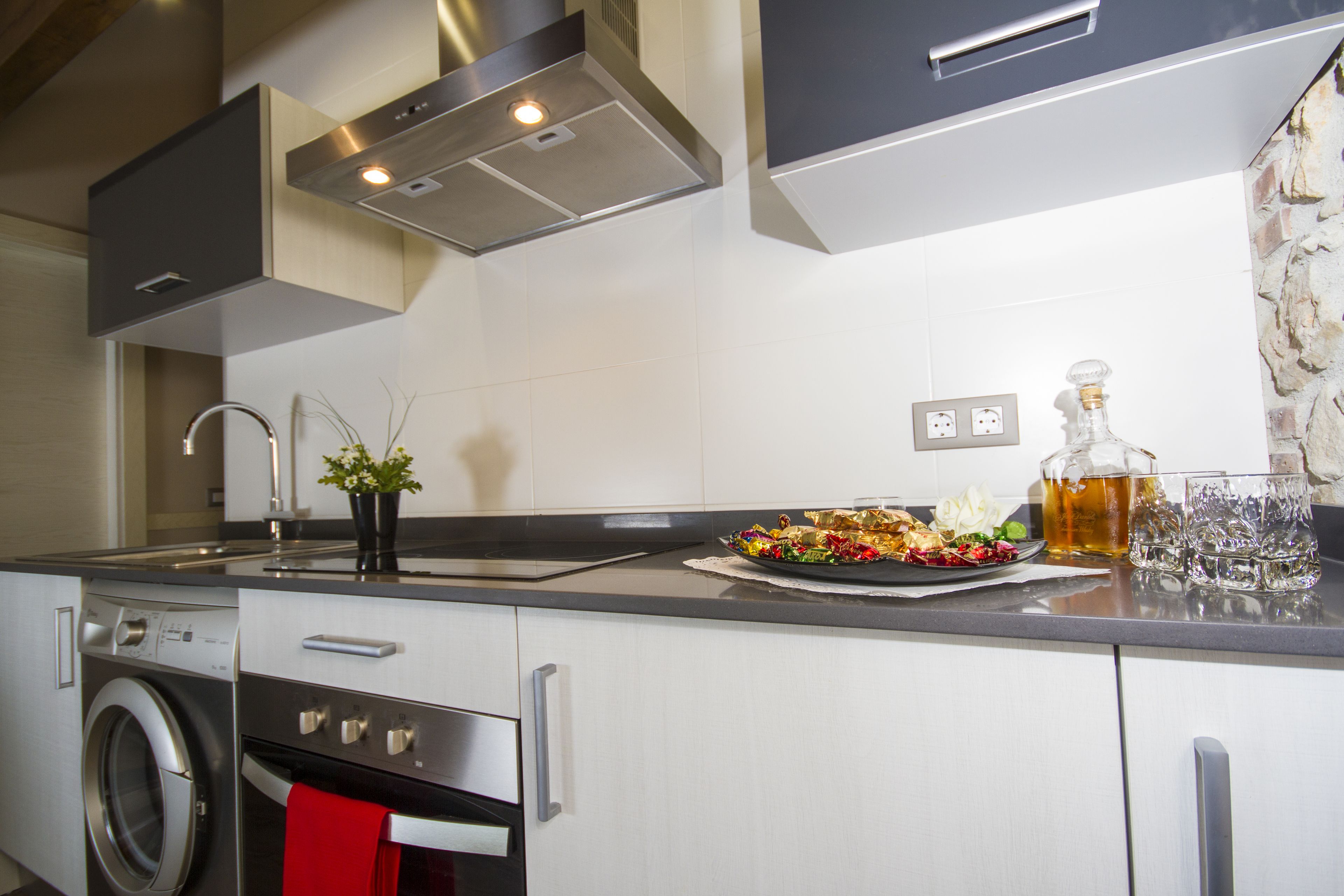 A modern kitchen with stainless steel appliances, a sink, and a countertop with a decorative plate and glasses.