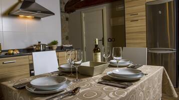 Una mesa lista para comer, con platos, vasos, cubiertos, una botella de vino y un cuenco de fruta.