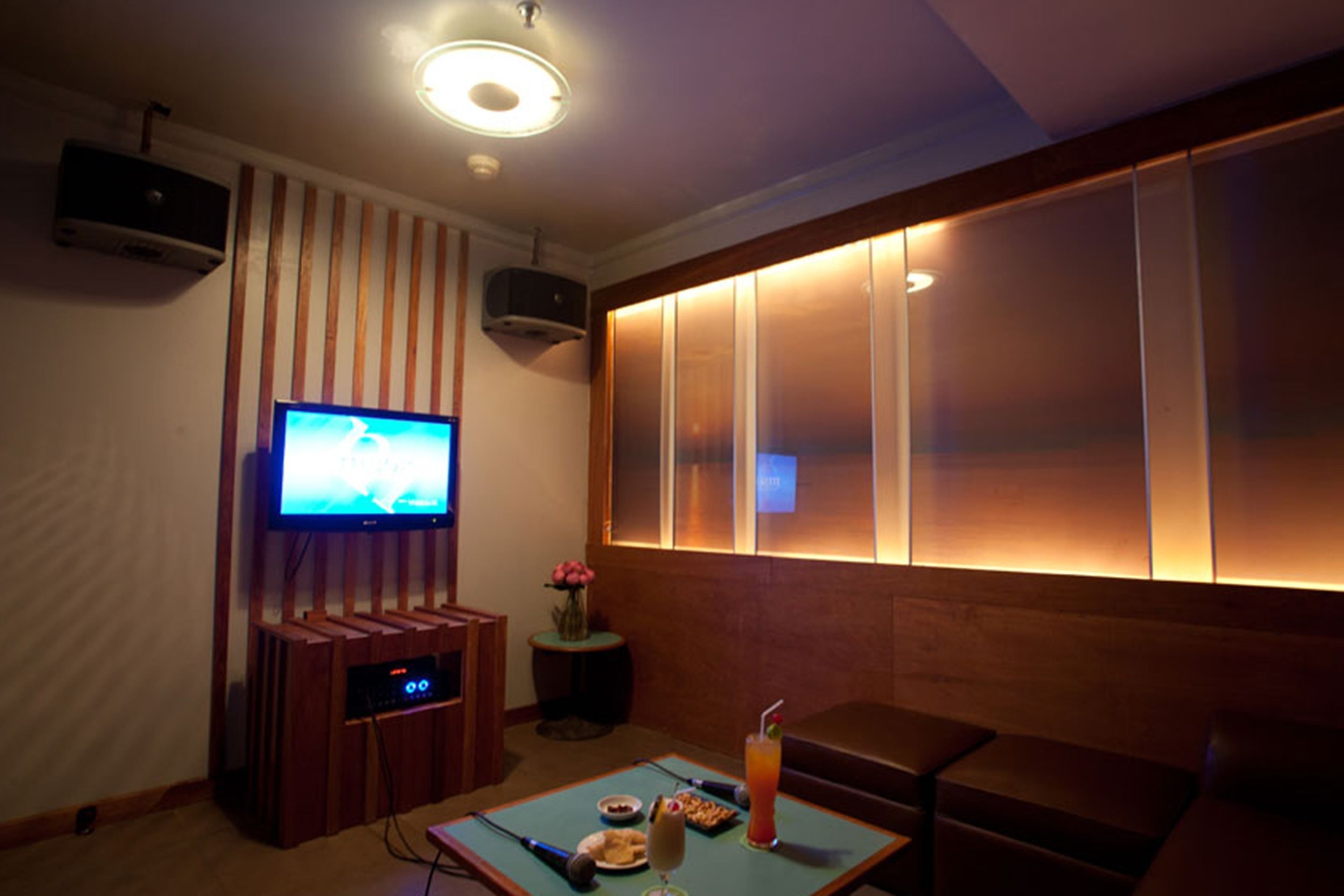 A cozy room with a flat-screen TV, a small table with snacks and a drink, and a comfortable seating area.