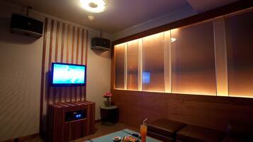 A cozy room with a flat-screen TV, a small table with snacks and a drink, and a comfortable seating area.