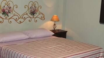 A neatly made bed with a striped bedspread, a bedside table with a lamp, and decorative wall art above the bed.