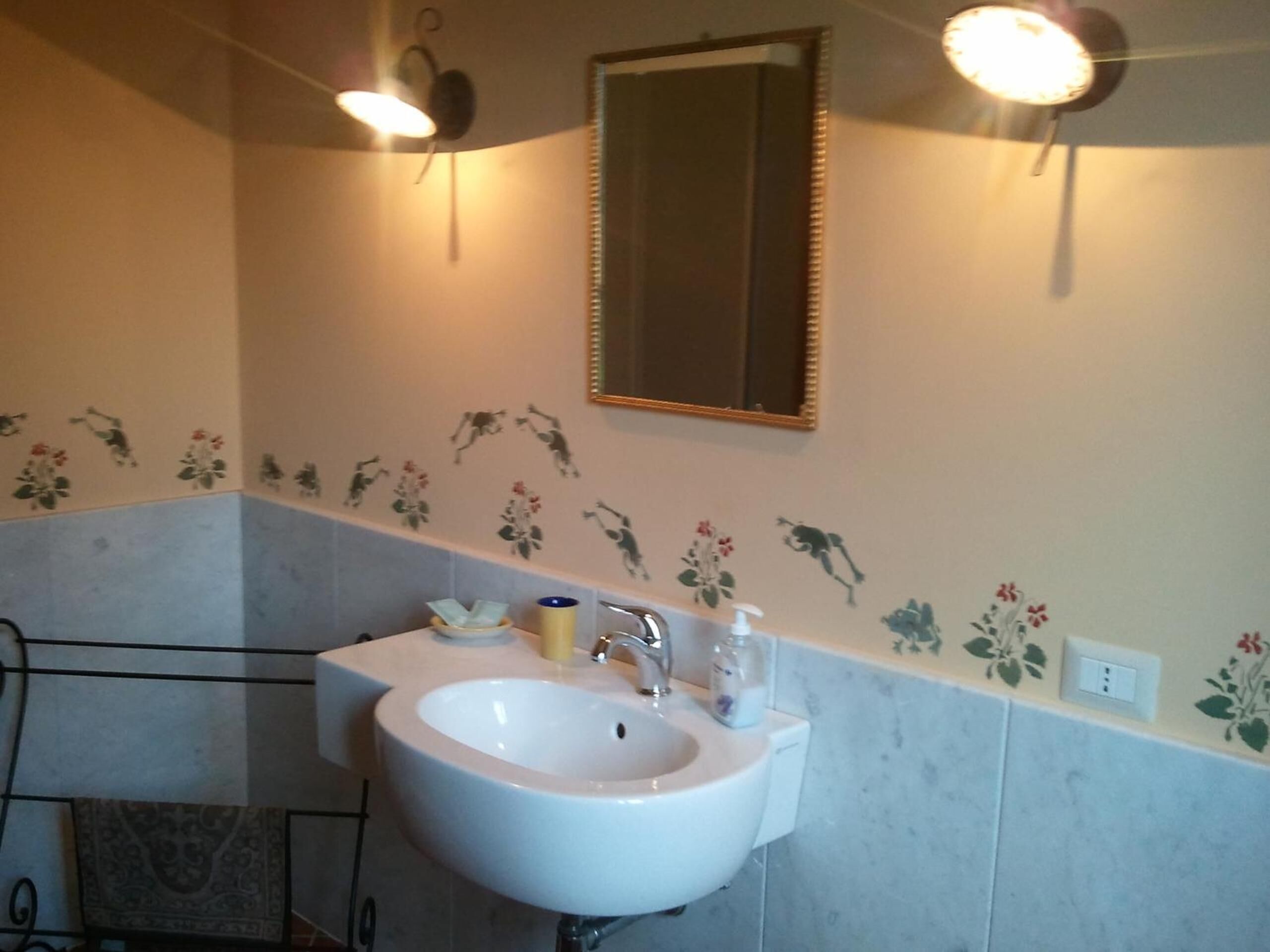 Un baño con un lavabo blanco, un espejo y adhesivos decorativos con motivos florales.