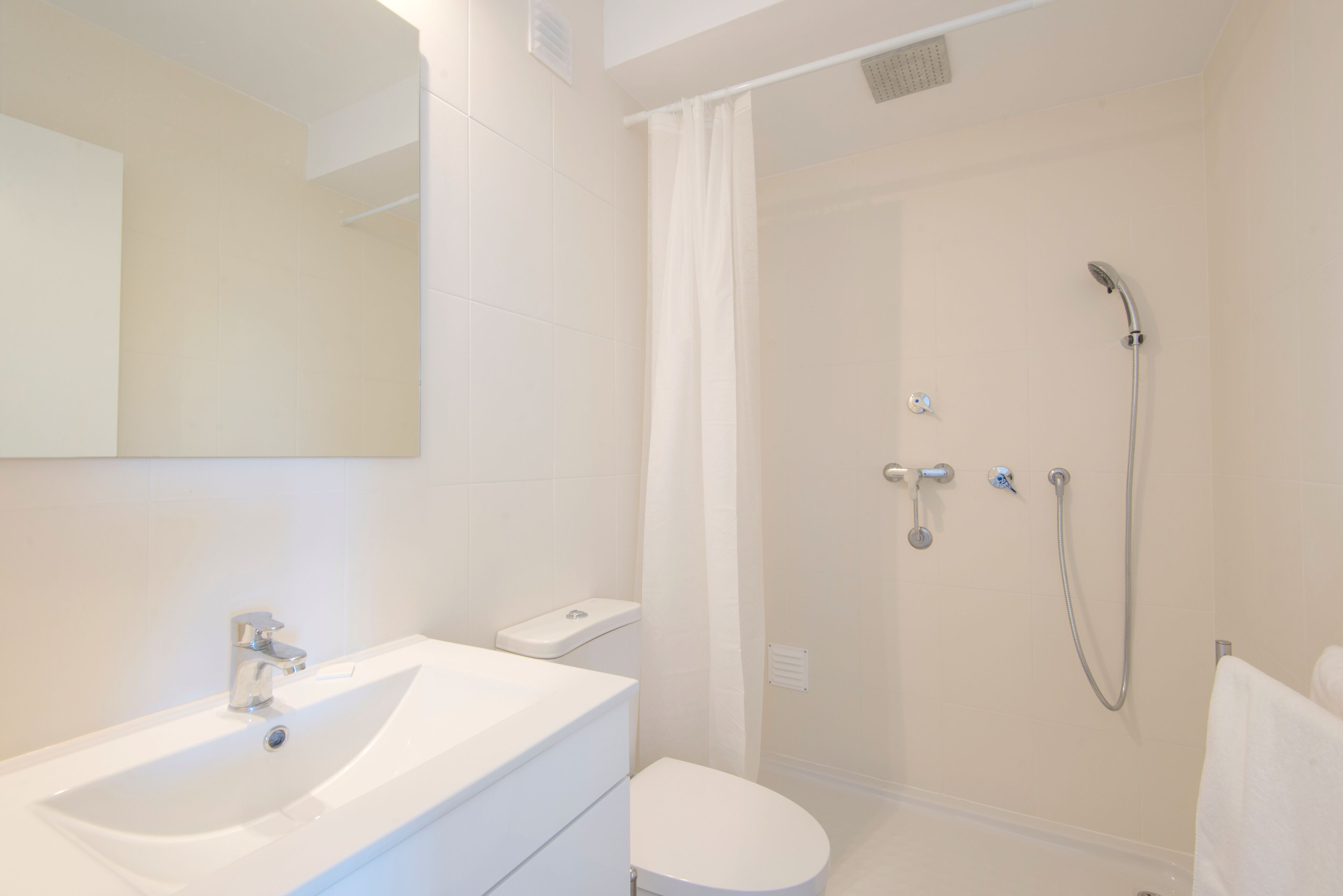 A modern bathroom with a white sink, toilet, and shower.