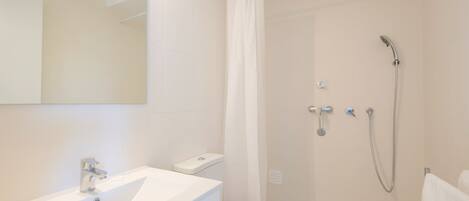 A modern bathroom with a white sink, toilet, and shower.