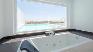 Un bagno moderno con un'ampia finestra, una vasca da bagno e vista su piscina e paesaggio.