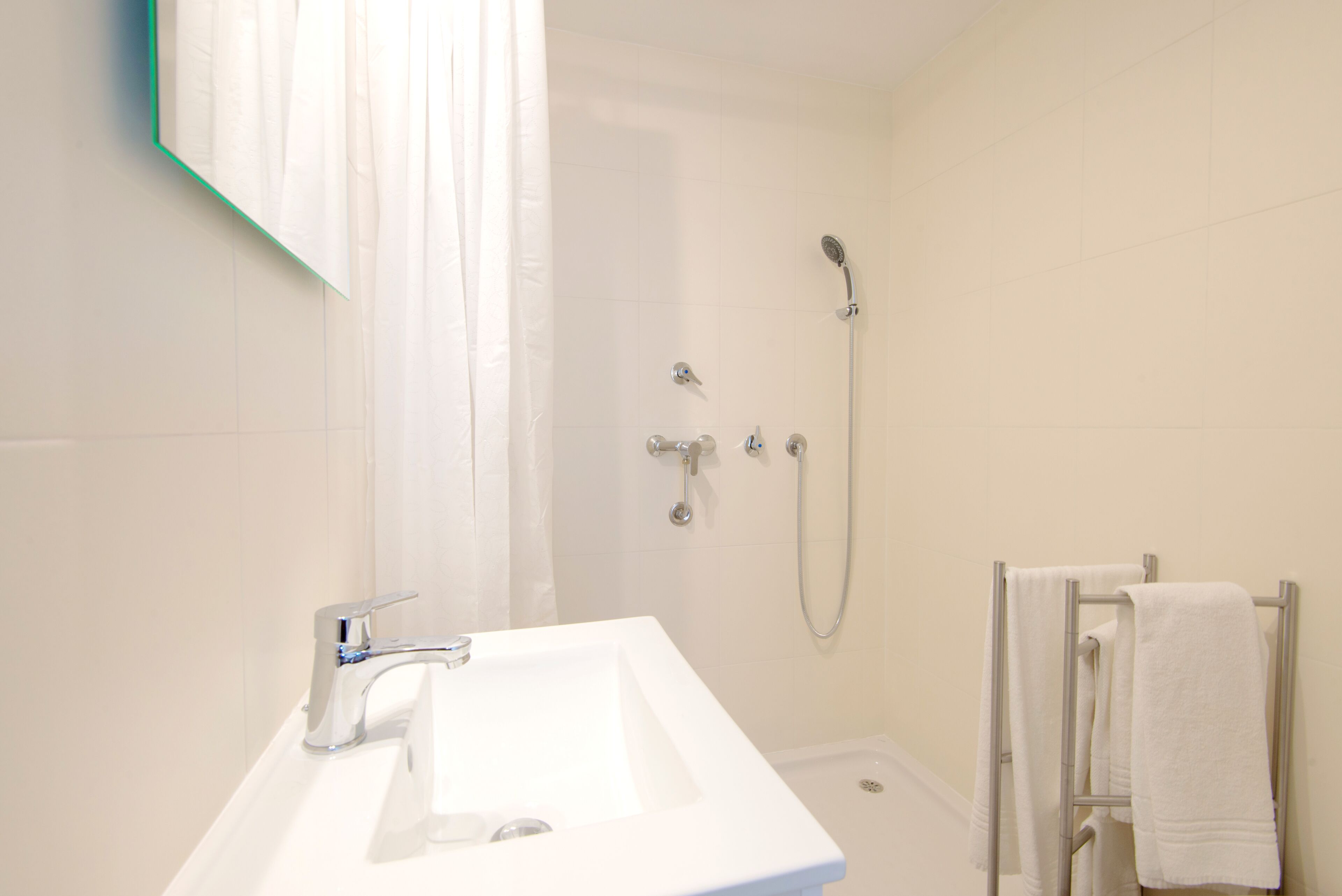 Une salle de bain avec un lavabo blanc, une douche et un porte-serviettes.