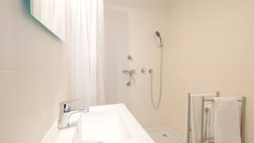 Une salle de bain avec un lavabo blanc, une douche et un porte-serviettes.