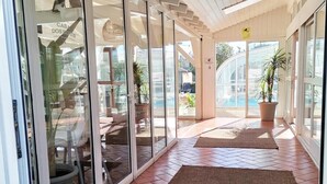Un'area esterna coperta con porte scorrevoli in vetro che si aprono su un patio con mobili da giardino e piante in vaso.