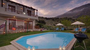 Un área de piscina con terraza de madera, sillas de descanso y una parrilla.