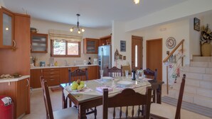 Una cocina moderna con armarios de madera, una mesa de comedor con sillas y una escalera que sube a un nivel superior.
