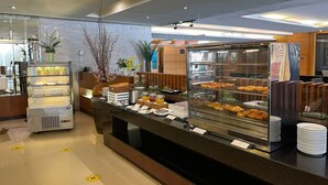 A buffet area with a variety of food items, a self-service beverage dispenser, and a refrigerated display case. - The Royal River Hotel (Bangkok)
