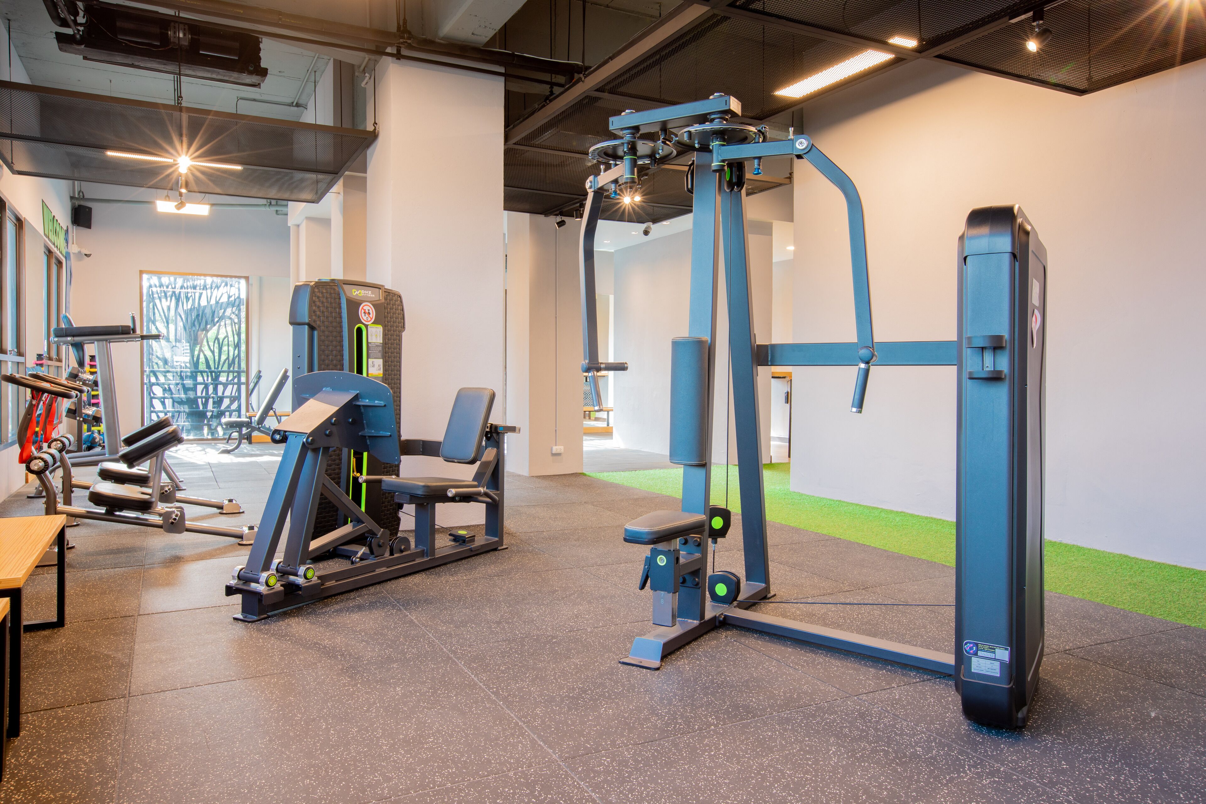 Ein Fitnessraum mit Trainingsgeräten, Laufband und einer Gewichtshalterung.