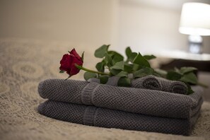 A rolled gray towel and a red rose on a textured surface. - Dogana d'Acqua Art B&B (Livorno)