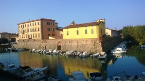 A marina with boats docked, a stone wall, and buildings with yellow and red facades. - Dogana d'Acqua Art B&B (Livorno)