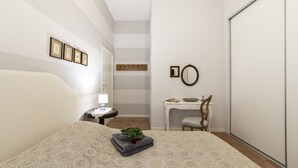 A bedroom with a bed, bedside table, lamp, chair, desk, and a mirror. - Dogana d'Acqua Art B&B (Livorno)