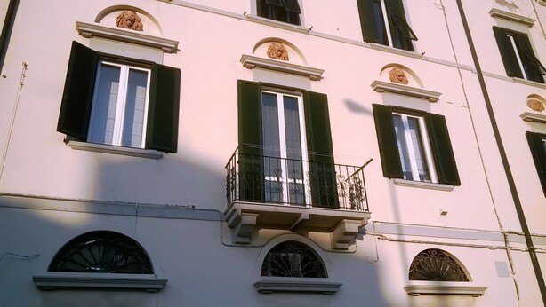 A building with multiple windows, some with shutters, and decorative lion heads above the windows. - Dogana d'Acqua Art B&B (Livorno)