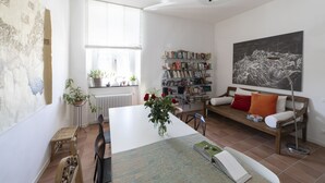 A spacious living room with a white sofa, a wooden coffee table, and a bookshelf filled with books. - Dogana d'Acqua Art B&B (Livorno)