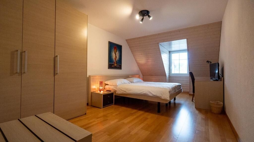 Ein Schlafzimmer mit Bett, Nachttisch, Lampe und Fernseher.