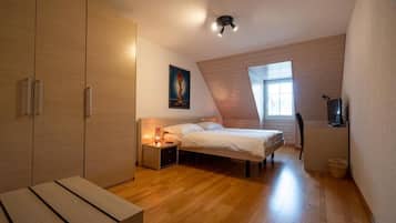 Ein Schlafzimmer mit Bett, Nachttisch, Lampe und Fernseher.