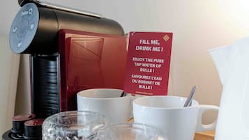 A coffee maker, a sign, cups, and a tray with glassware.