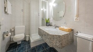 Un baño con inodoro, lavamanos, espejo y ducha.
