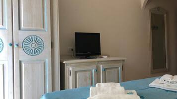 Una camera d'albergo con un letto, una televisione su un comò e uno specchio a parete.
