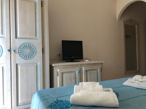 A hotel room with a bed, a television on a dresser, and a mirror on the wall.