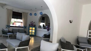 Un área de descanso moderna con muebles de mimbre, un aparador azul y vistas al exterior.
