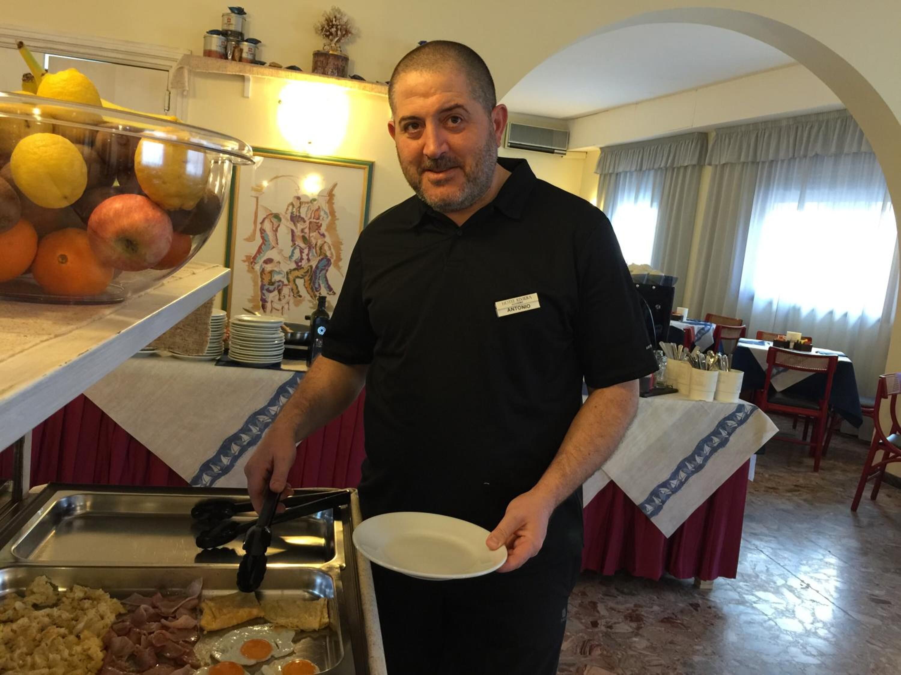A buffet setup with various food items and a person serving.