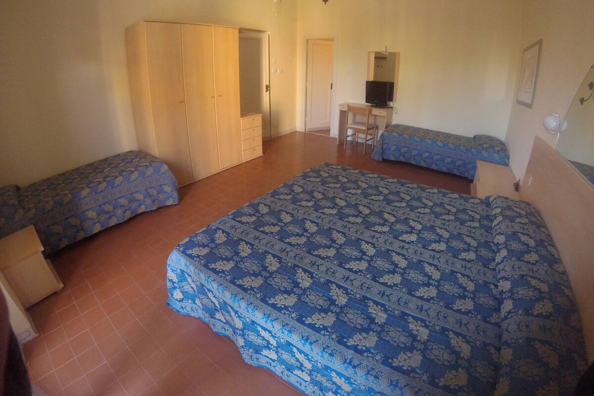 A bedroom with two beds, a wardrobe, a desk, and a chair.