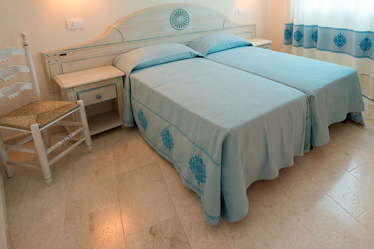 A bedroom with two beds, a nightstand, a chair, and a small table.